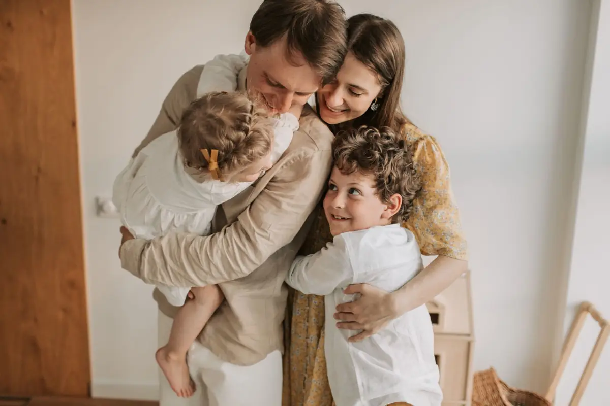 Madre y padre abrazando a sus dos hijos en casa